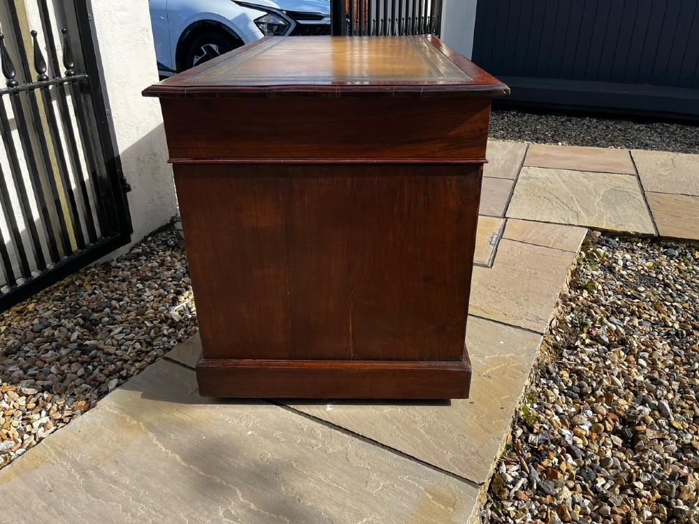 A late 19th-century mahogany pedestal desk featuring nine drawers with brass handles and a plinth base. View VIII