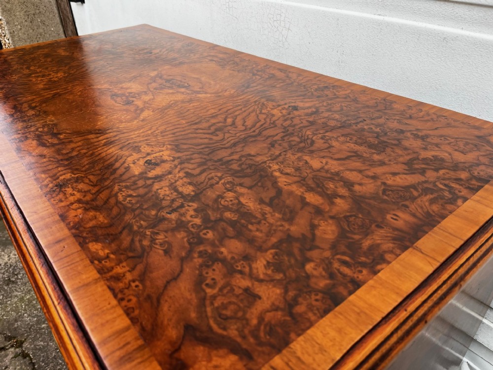 A 19th-century burr walnut veneered chest of drawers featuring two short over three long drawers with brass drop handles and bracket feet. View III