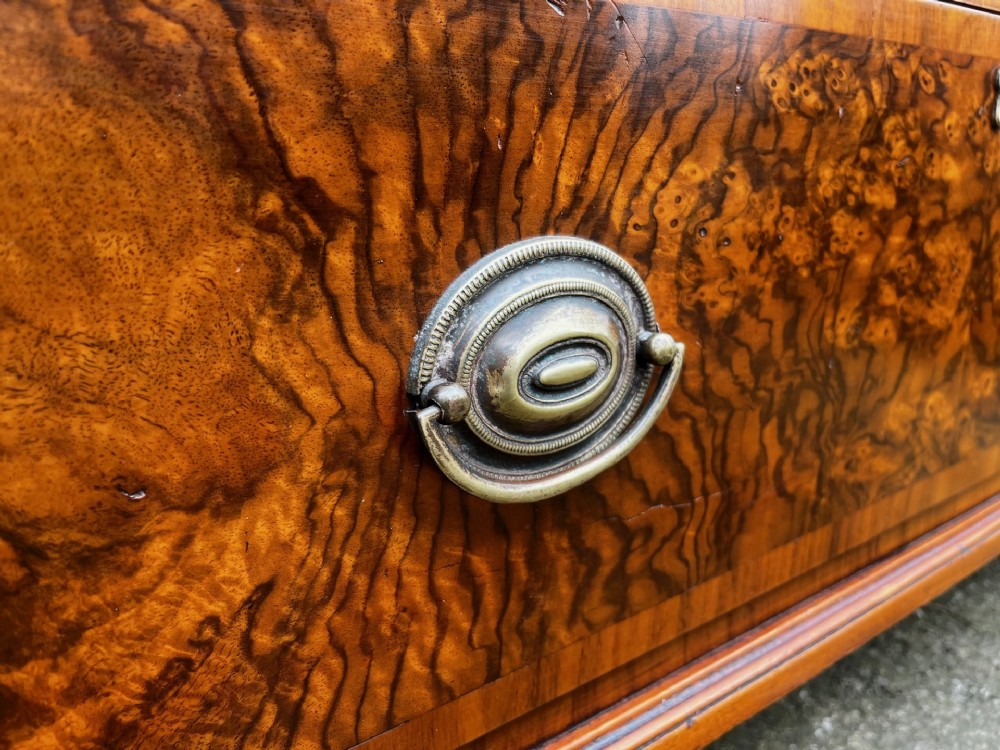 A 19th-century burr walnut veneered chest of drawers featuring two short over three long drawers with brass drop handles and bracket feet. View IX