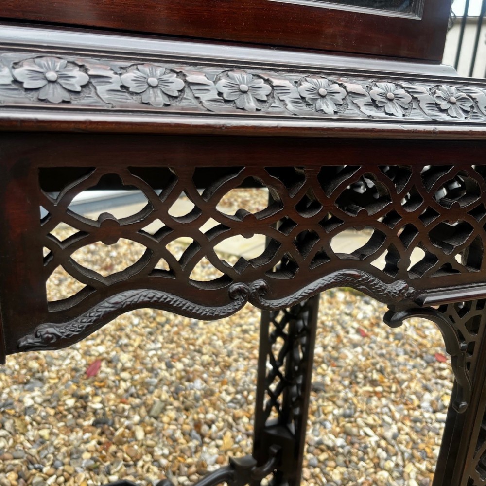 A tall dark mahogany Chinese Chippendale style display cabinet featuring glazed doors with gothic tracery, intricate pierced fretwork gallery, and a decorative carved stand with lattice legs. View III
