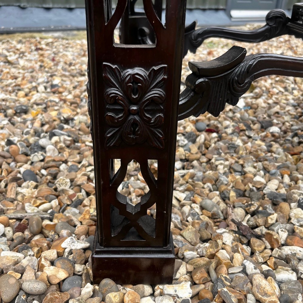 A tall dark mahogany Chinese Chippendale style display cabinet featuring glazed doors with gothic tracery, intricate pierced fretwork gallery, and a decorative carved stand with lattice legs. View IV