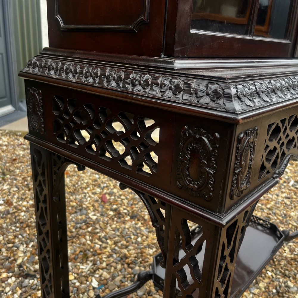 A tall dark mahogany Chinese Chippendale style display cabinet featuring glazed doors with gothic tracery, intricate pierced fretwork gallery, and a decorative carved stand with lattice legs. View V