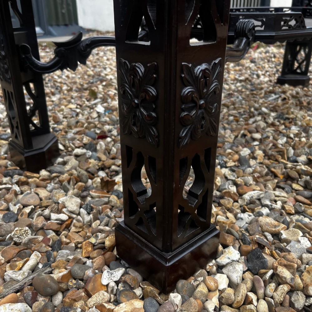 A tall dark mahogany Chinese Chippendale style display cabinet featuring glazed doors with gothic tracery, intricate pierced fretwork gallery, and a decorative carved stand with lattice legs. View VI