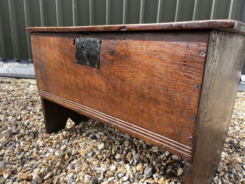 A solid dark oak 17th-century plank coffer featuring simple moulded border detailing, slab sides forming legs, and an iron lock plate. View IV