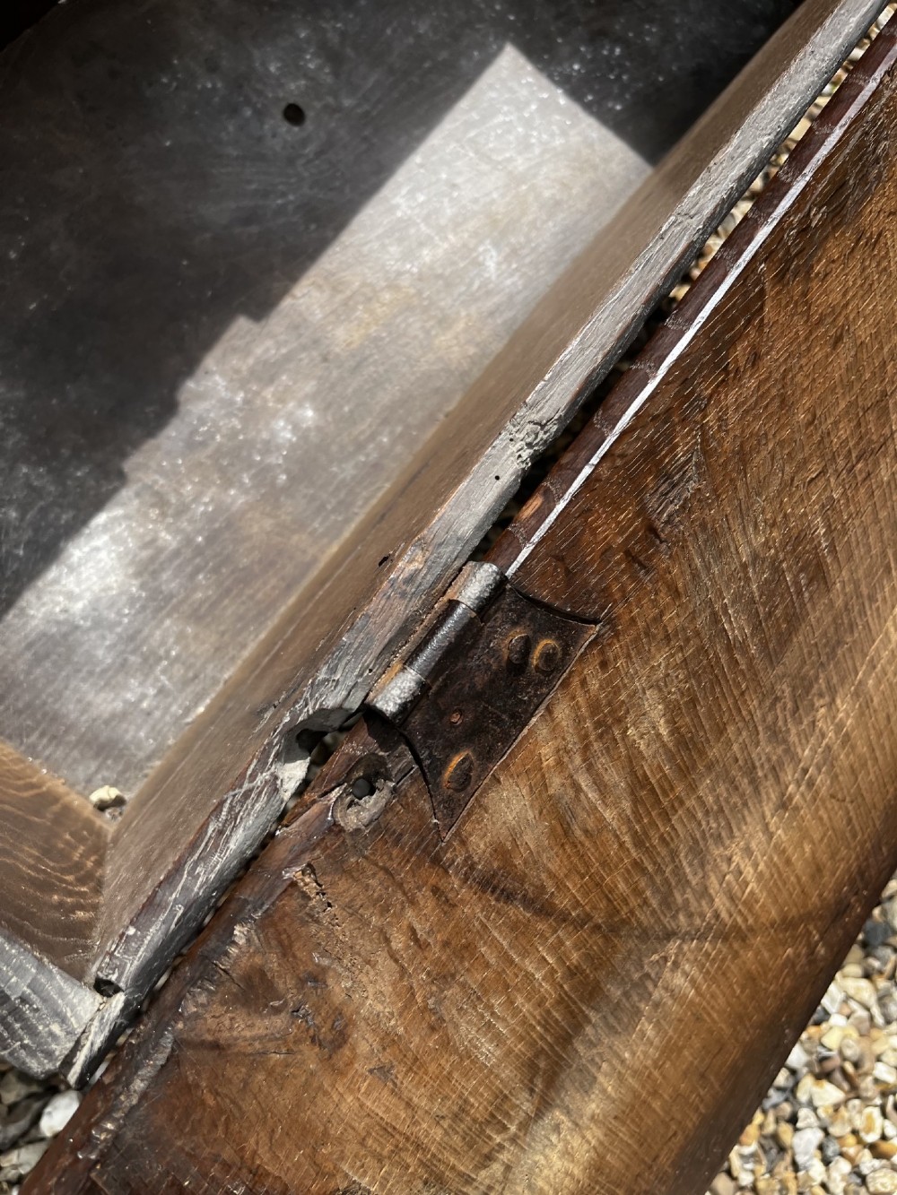 A solid dark oak 17th-century plank coffer featuring simple moulded border detailing, slab sides forming legs, and an iron lock plate. View VIII