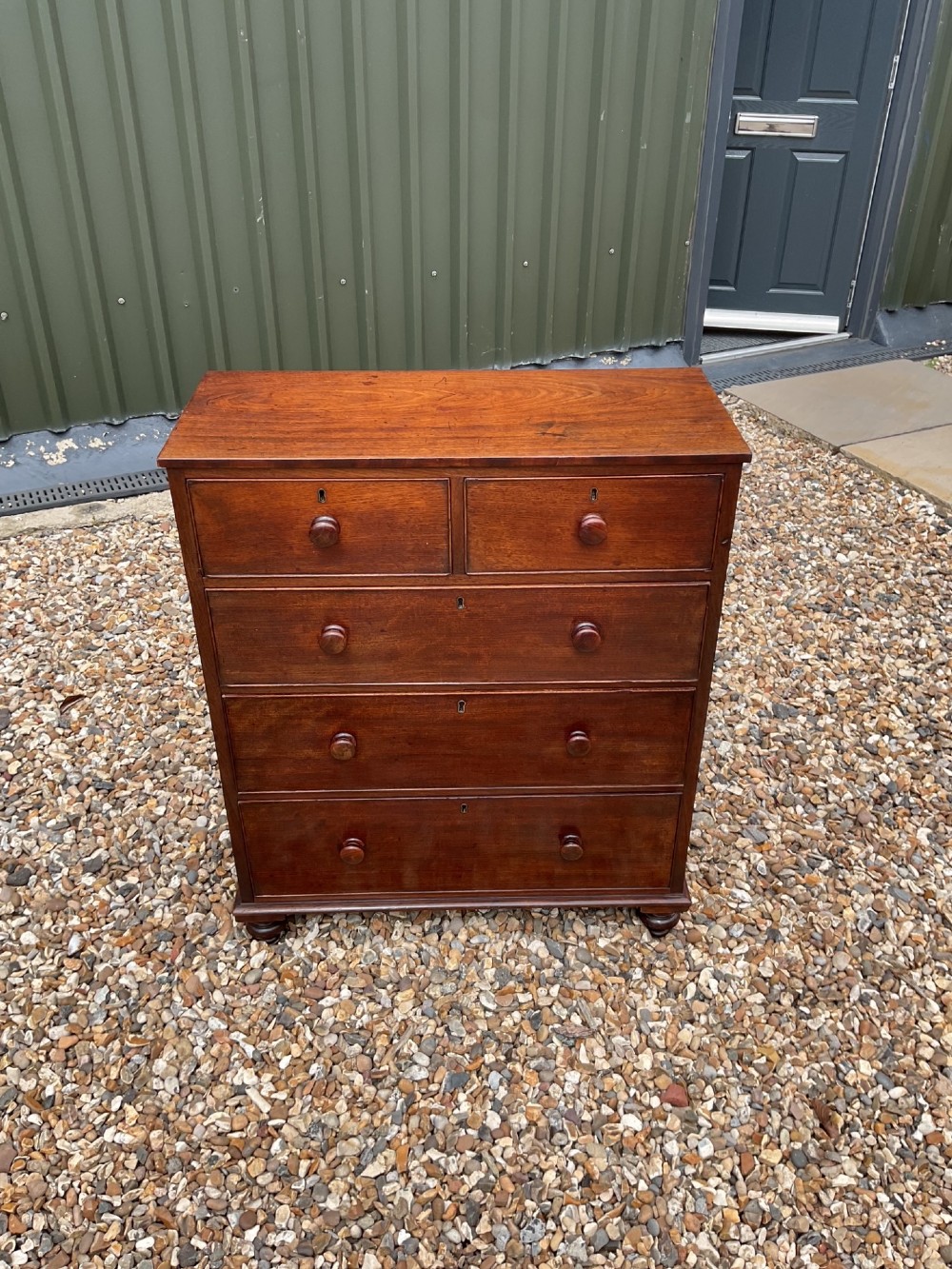 An early Victorian mahogany chest of drawers featuring a two-over-three drawer layout with turned wooden knob handles and short turned feet. View II