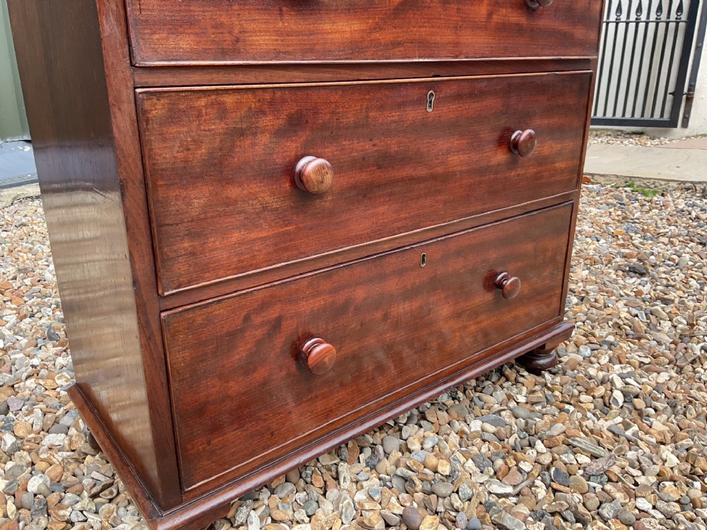 An early Victorian mahogany chest of drawers featuring a two-over-three drawer layout with turned wooden knob handles and short turned feet. View IV