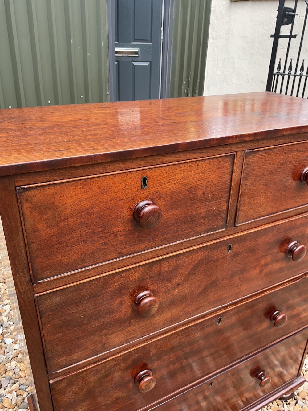 An early Victorian mahogany chest of drawers featuring a two-over-three drawer layout with turned wooden knob handles and short turned feet. View V