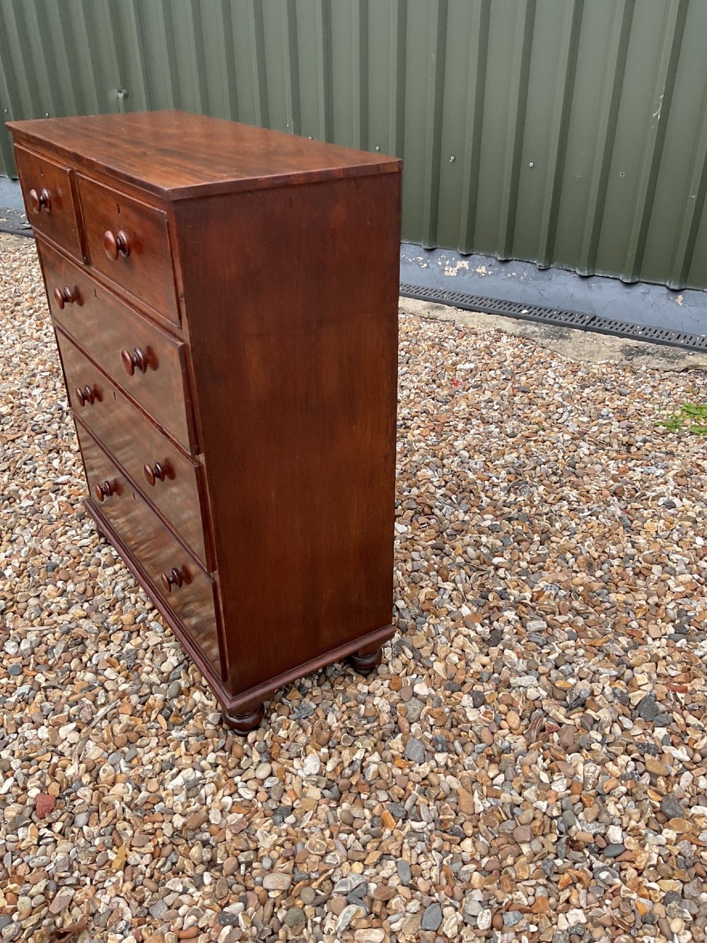 An early Victorian mahogany chest of drawers featuring a two-over-three drawer layout with turned wooden knob handles and short turned feet. View VI