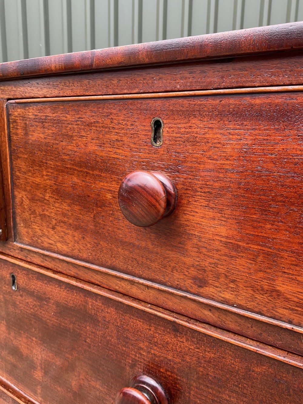 An early Victorian mahogany chest of drawers featuring a two-over-three drawer layout with turned wooden knob handles and short turned feet. View VIII