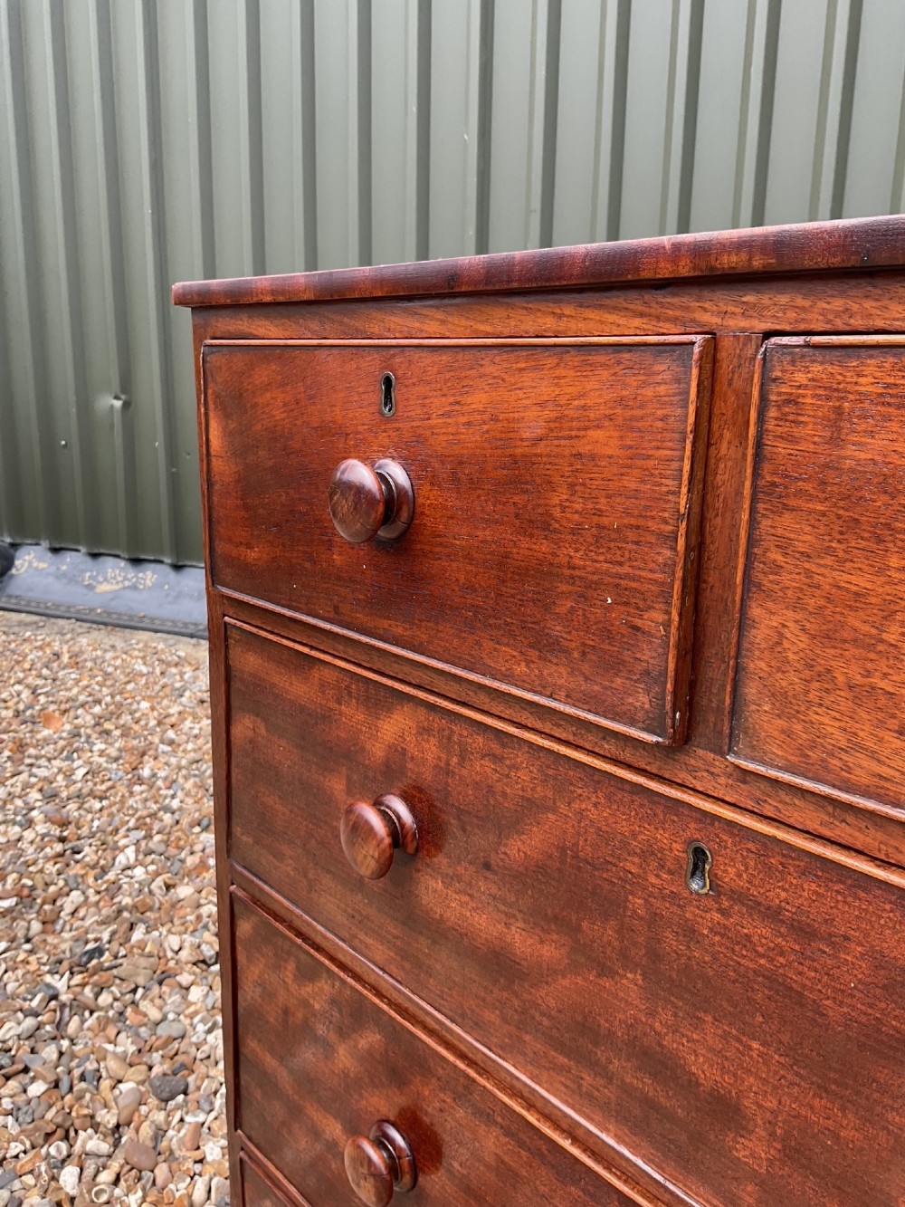 An early Victorian mahogany chest of drawers featuring a two-over-three drawer layout with turned wooden knob handles and short turned feet. View IX