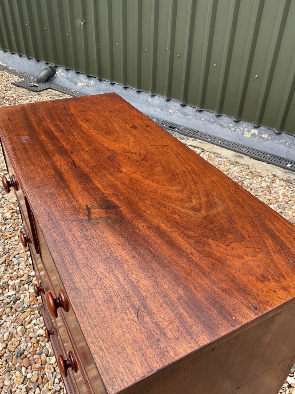 An early Victorian mahogany chest of drawers featuring a two-over-three drawer layout with turned wooden knob handles and short turned feet. View X