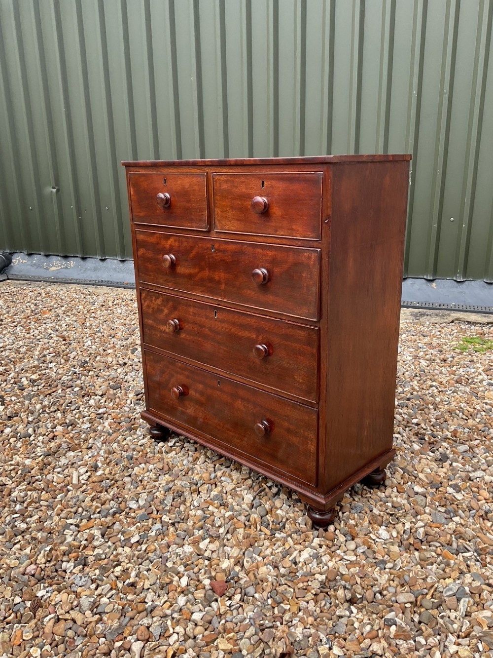 An early Victorian mahogany chest of drawers featuring a two-over-three drawer layout with turned wooden knob handles and short turned feet. View XII