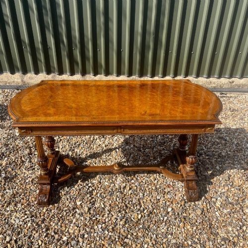 A Victorian burr walnut library table with shaped ends, fluted dual end supports, a low stretcher, and gilded ormolu mounts. View II