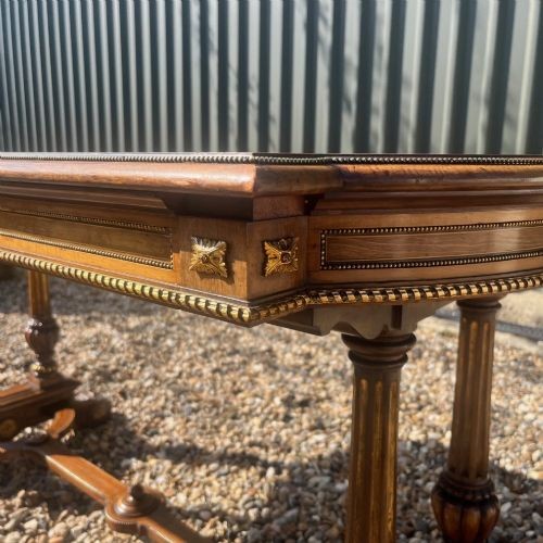 A Victorian burr walnut library table with shaped ends, fluted dual end supports, a low stretcher, and gilded ormolu mounts. View V