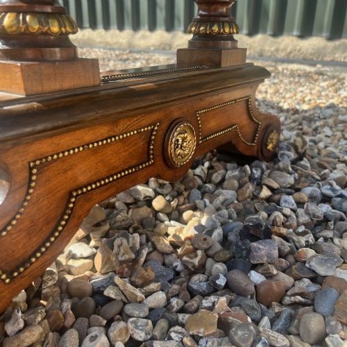 A Victorian burr walnut library table with shaped ends, fluted dual end supports, a low stretcher, and gilded ormolu mounts. View VI