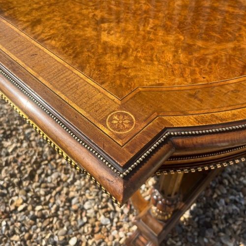A Victorian burr walnut library table with shaped ends, fluted dual end supports, a low stretcher, and gilded ormolu mounts. View VIII