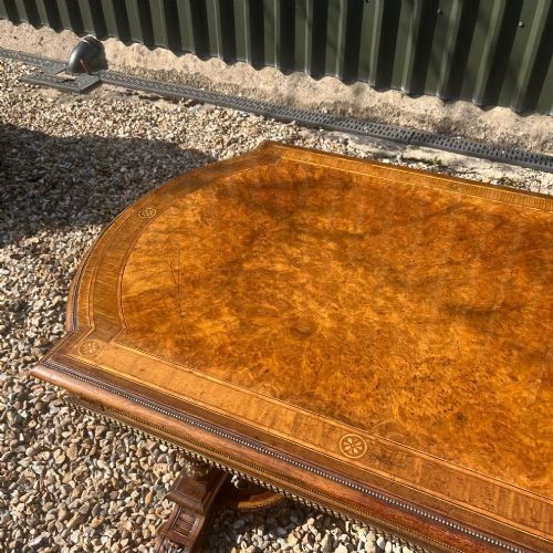 A Victorian burr walnut library table with shaped ends, fluted dual end supports, a low stretcher, and gilded ormolu mounts. View XII