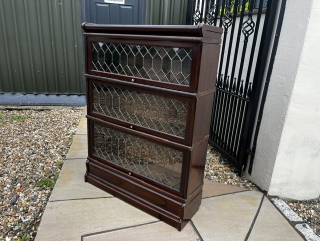 A three-tier Edwardian solid mahogany Globe Wernicke stacking bookcase featuring diamond-leaded glazed doors and a plinth base. View II