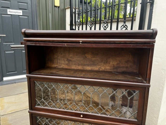 A three-tier Edwardian solid mahogany Globe Wernicke stacking bookcase featuring diamond-leaded glazed doors and a plinth base. View IX