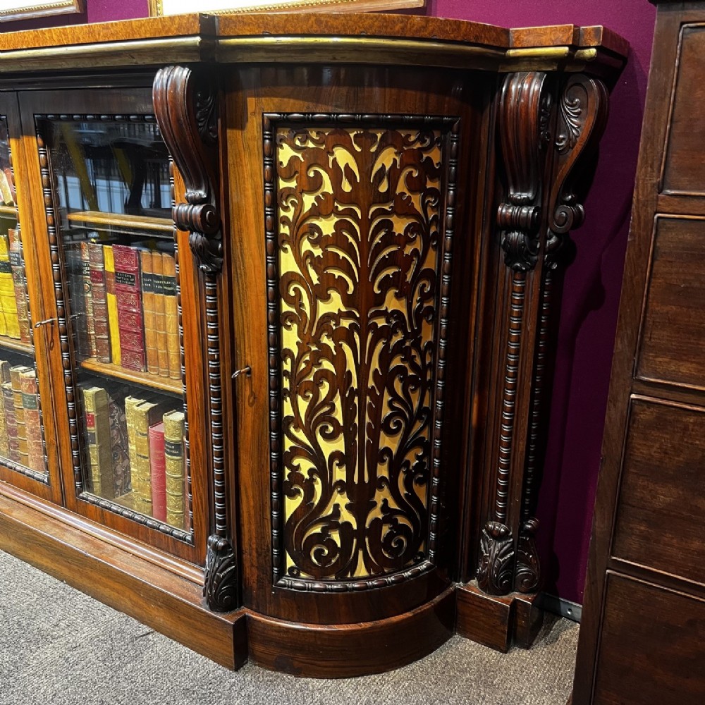An early Victorian Goncalo Alves and amboyna low bookcase credenza featuring glazed doors and carved corbels. View II