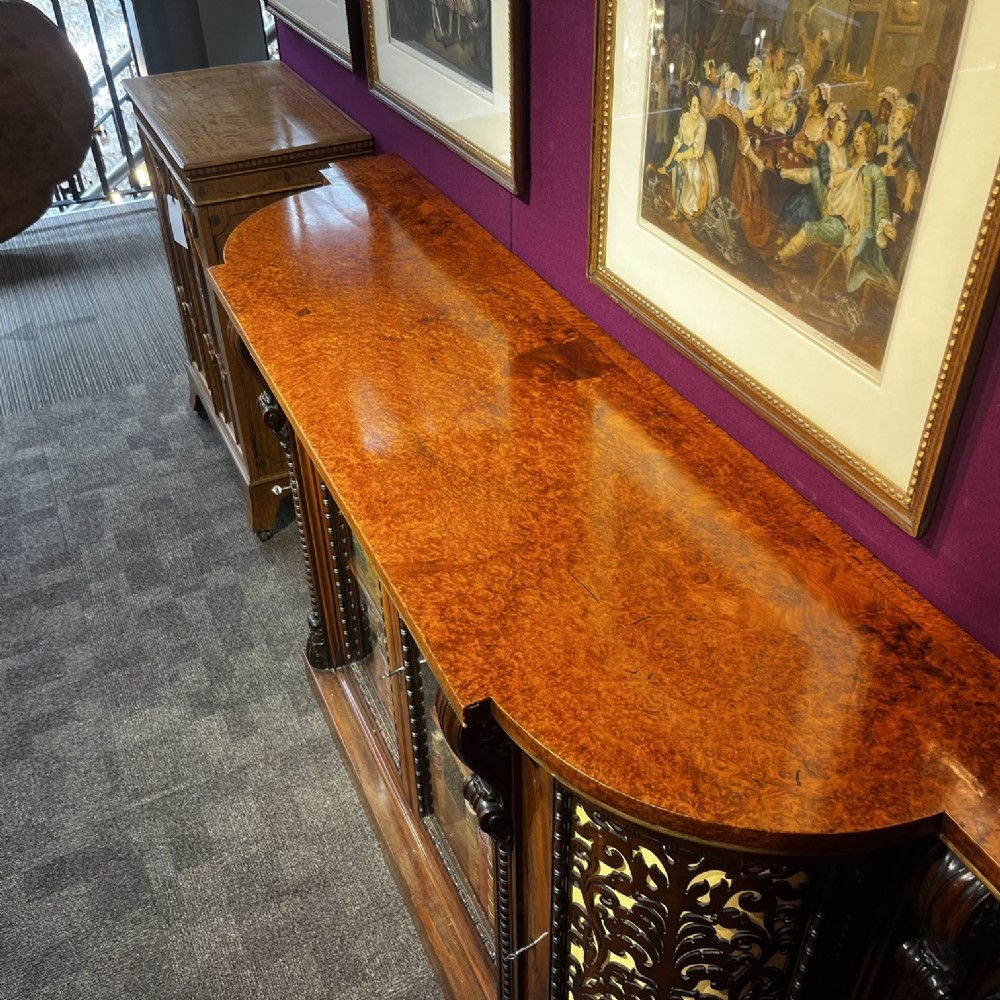 An early Victorian Goncalo Alves and amboyna low bookcase credenza featuring glazed doors and carved corbels. View V
