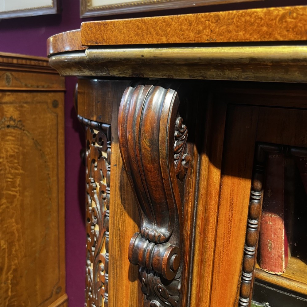 An early Victorian Goncalo Alves and amboyna low bookcase credenza featuring glazed doors and carved corbels. View IX