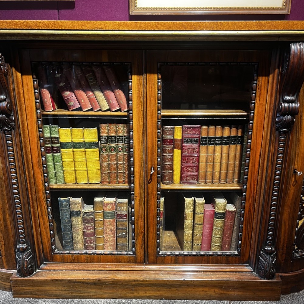 An early Victorian Goncalo Alves and amboyna low bookcase credenza featuring glazed doors and carved corbels. View XI
