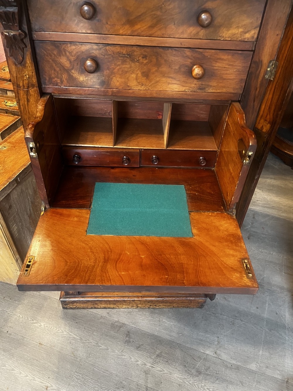A tall Victorian walnut Wellington chest featuring multiple graduated drawers with turned wooden handles, carved top corbels, and a side locking mechanism. View VII