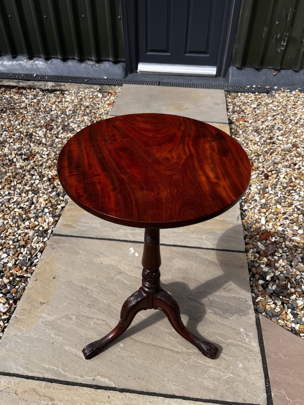 A 19th-century mahogany tripod occasional table featuring a circular polished top, turned central stem, and three carved cabriole legs.