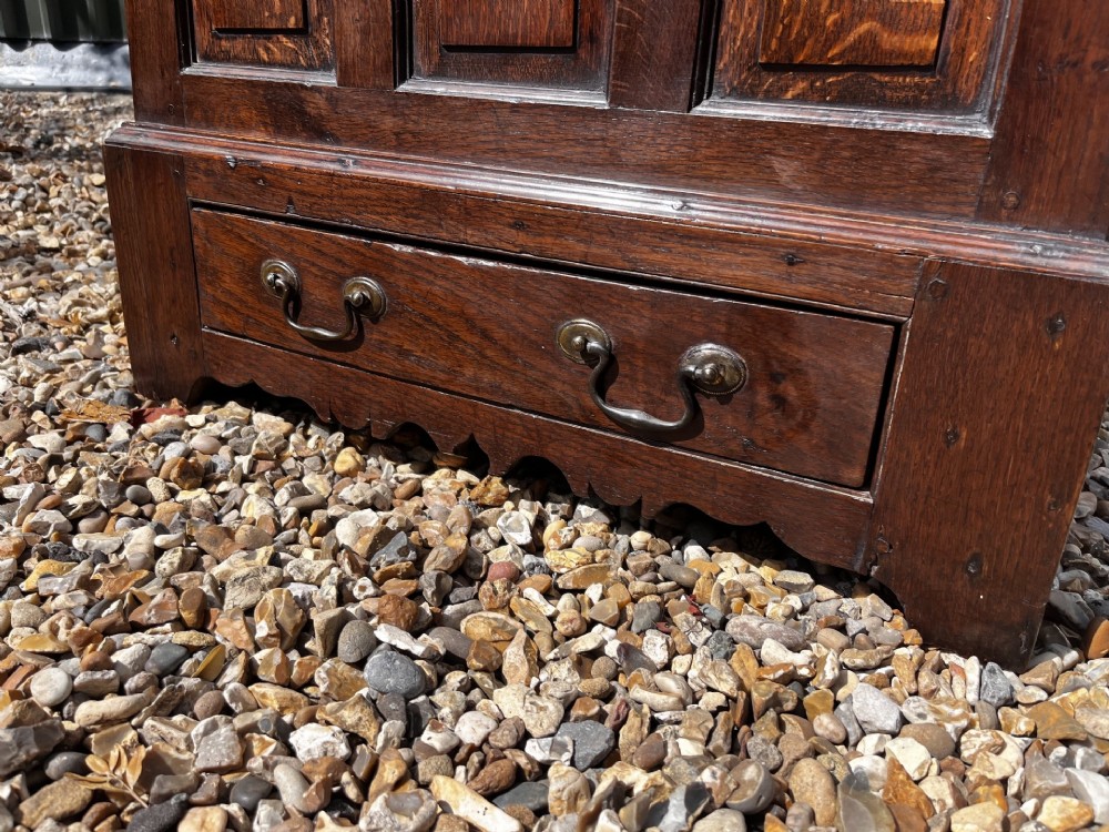 An eighteenth-century dark oak Welsh coffer bach featuring three fielded front panels, a lower drawer with brass handles, and a hinged lid. View IV