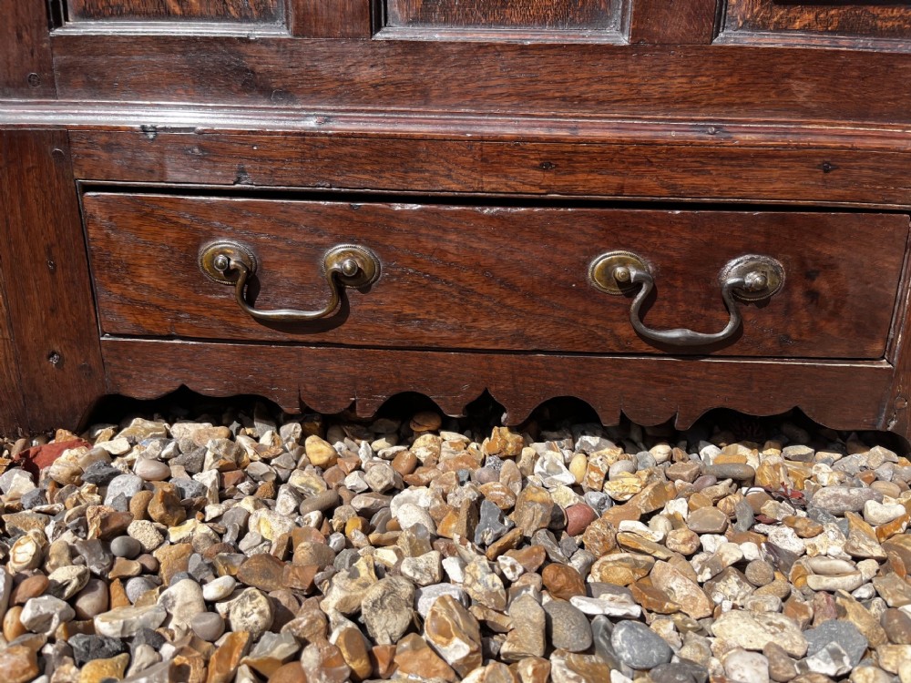 An eighteenth-century dark oak Welsh coffer bach featuring three fielded front panels, a lower drawer with brass handles, and a hinged lid. View VI