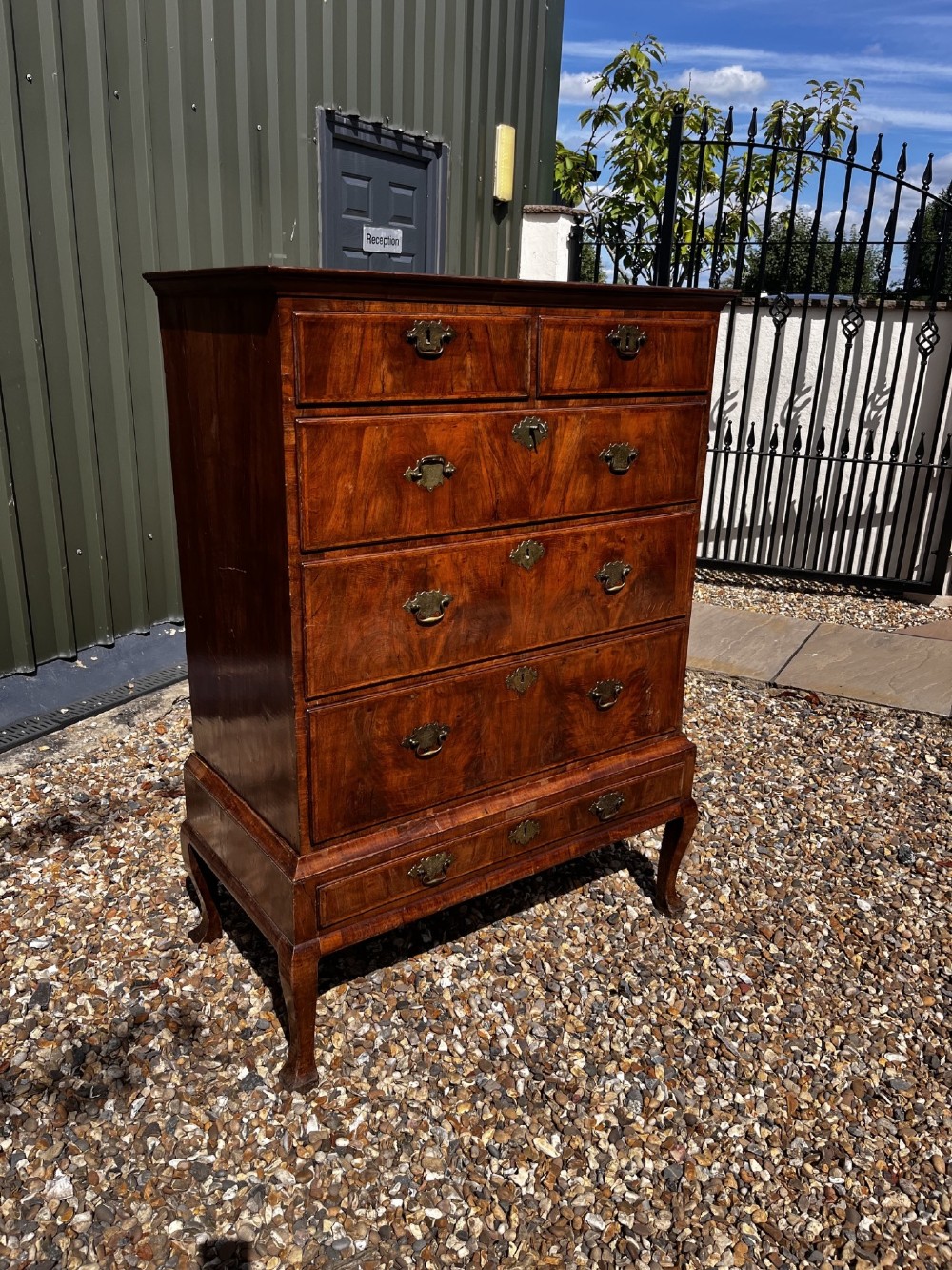 An 18th-century George II walnut chest on stand with brass handles, keyhole escutcheons, and cabriole legs.
