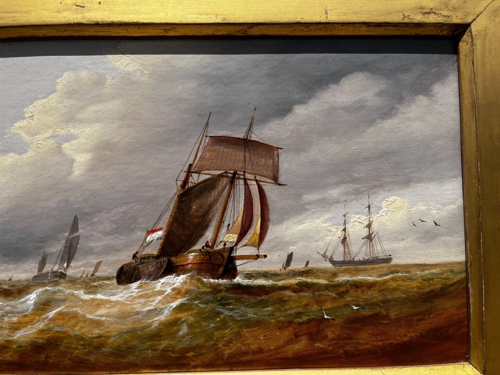 A pair of Victorian marine oil paintings depicting sailing ships on choppy coastal waters, framed in matching gilded rectangular frames with brass nameplates. View V