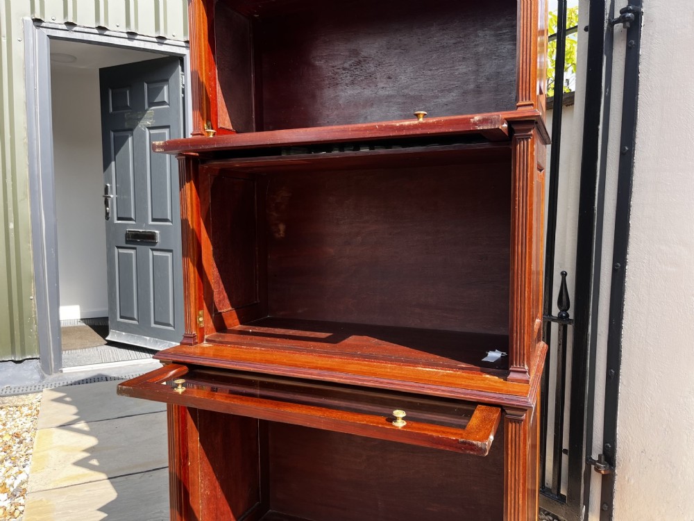 A four-tier solid mahogany barrister stacking bookcase featuring glazed up-and-over doors with brass knobs and a moulded top cornice. View V