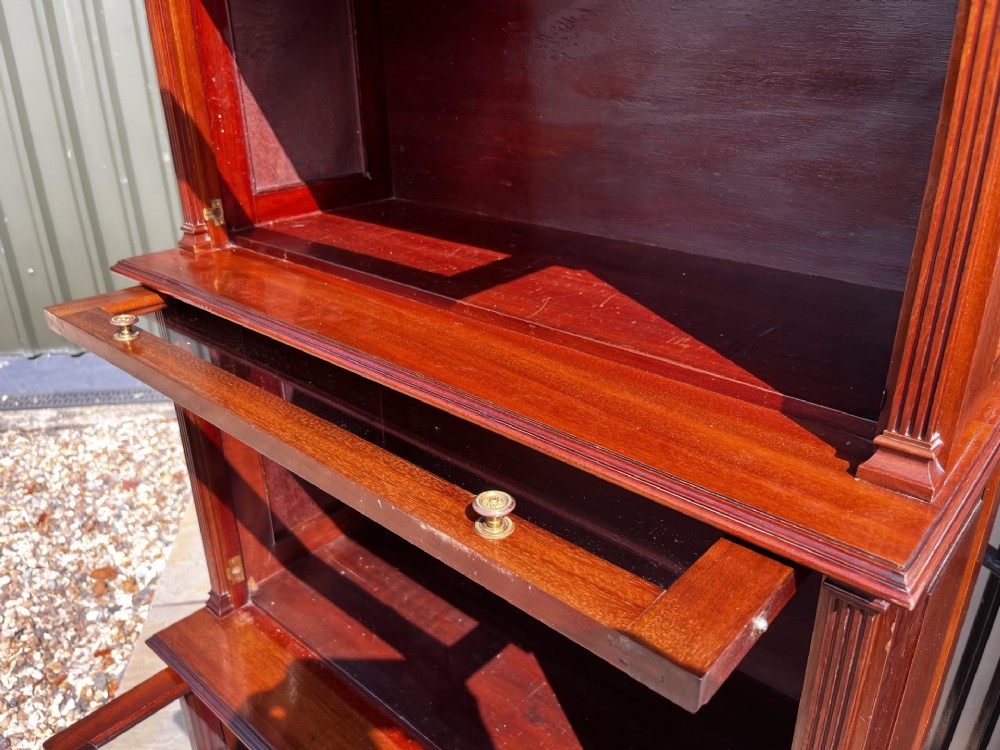 A four-tier solid mahogany barrister stacking bookcase featuring glazed up-and-over doors with brass knobs and a moulded top cornice. View VII