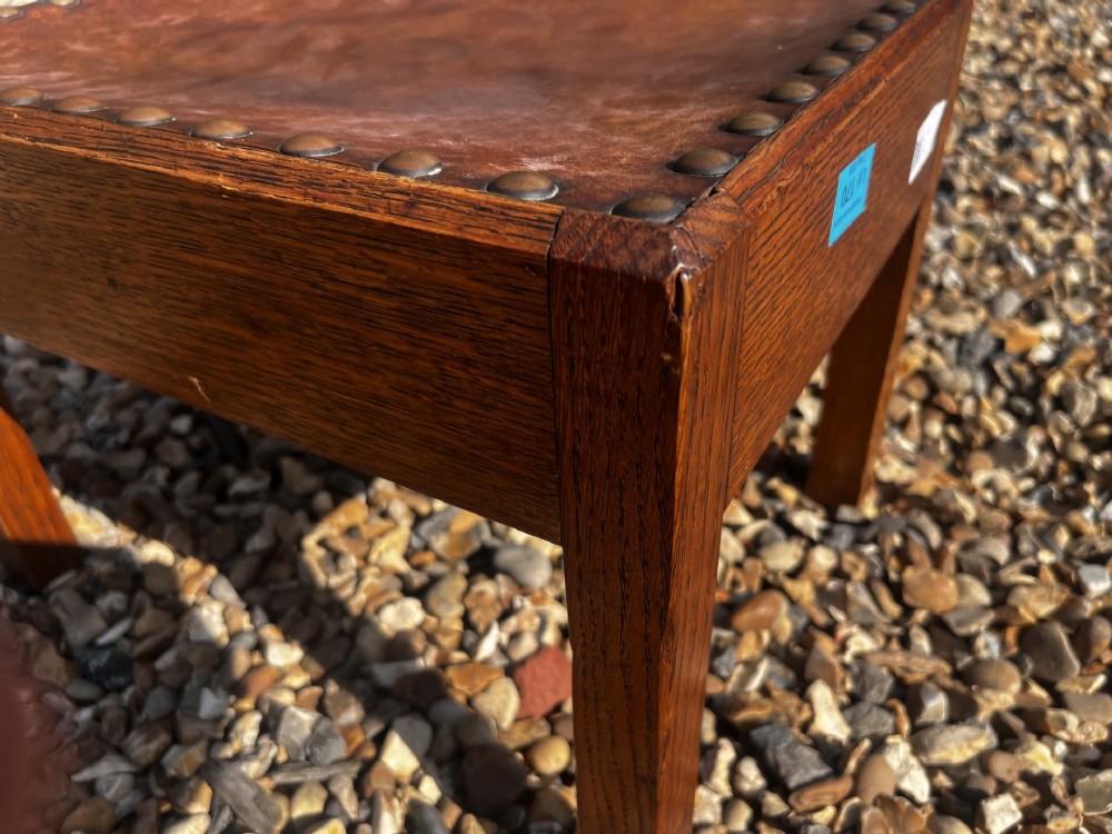 A rectangular Arts and Crafts oak stool featuring a brown leather top secured with a row of decorative metal studs around the rim. View V