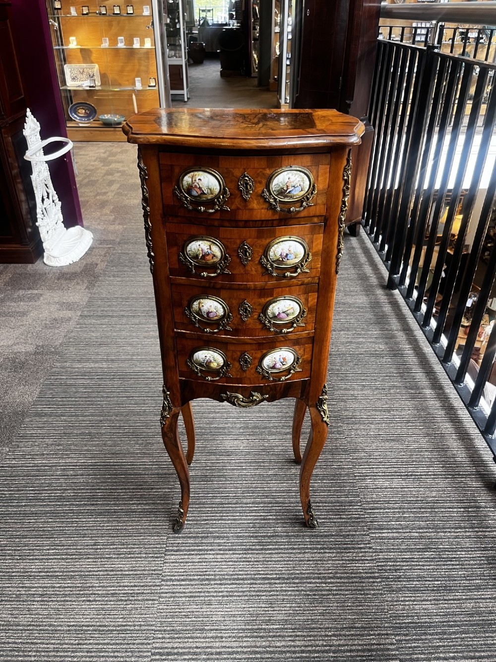 A late nineteenth-century walnut serpentine chest of four drawers featuring hand-painted oval porcelain plaques, ornate metal mounts, and slender cabriole legs.