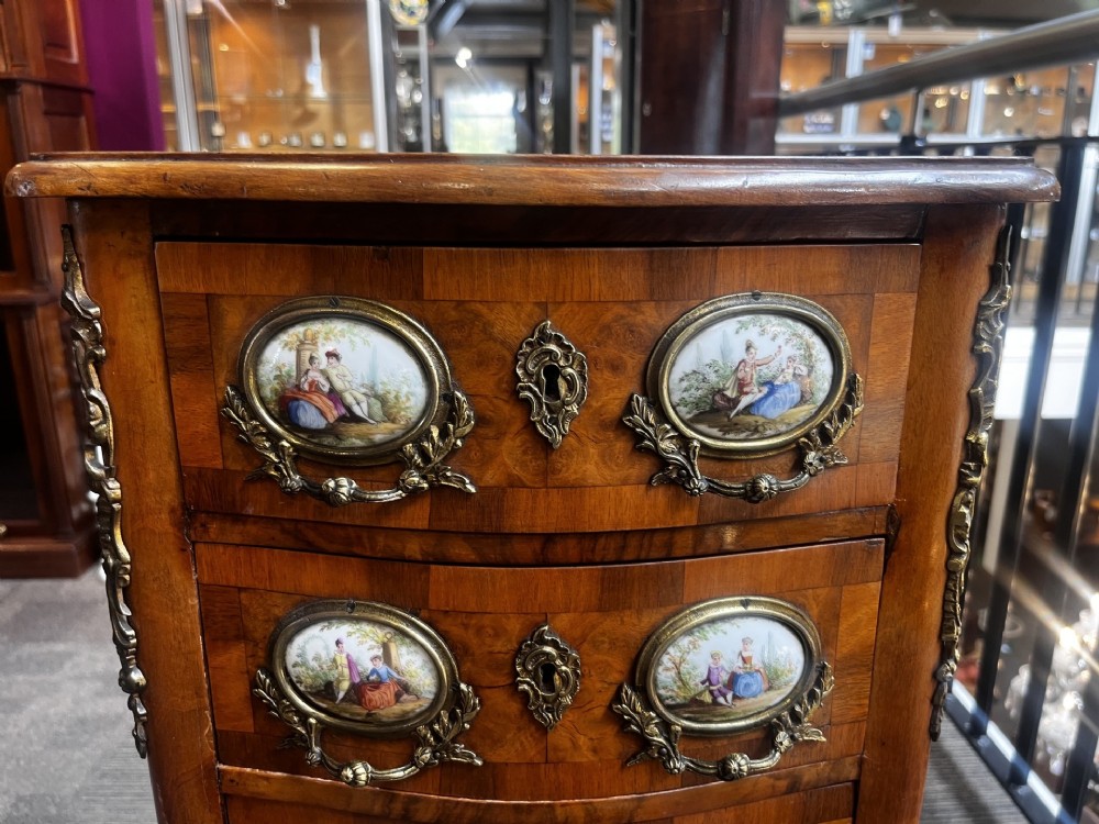 A late nineteenth-century walnut serpentine chest of four drawers featuring hand-painted oval porcelain plaques, ornate metal mounts, and slender cabriole legs. View III