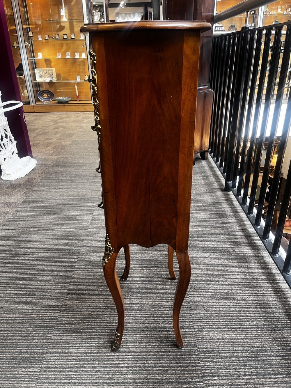A late nineteenth-century walnut serpentine chest of four drawers featuring hand-painted oval porcelain plaques, ornate metal mounts, and slender cabriole legs. View VII