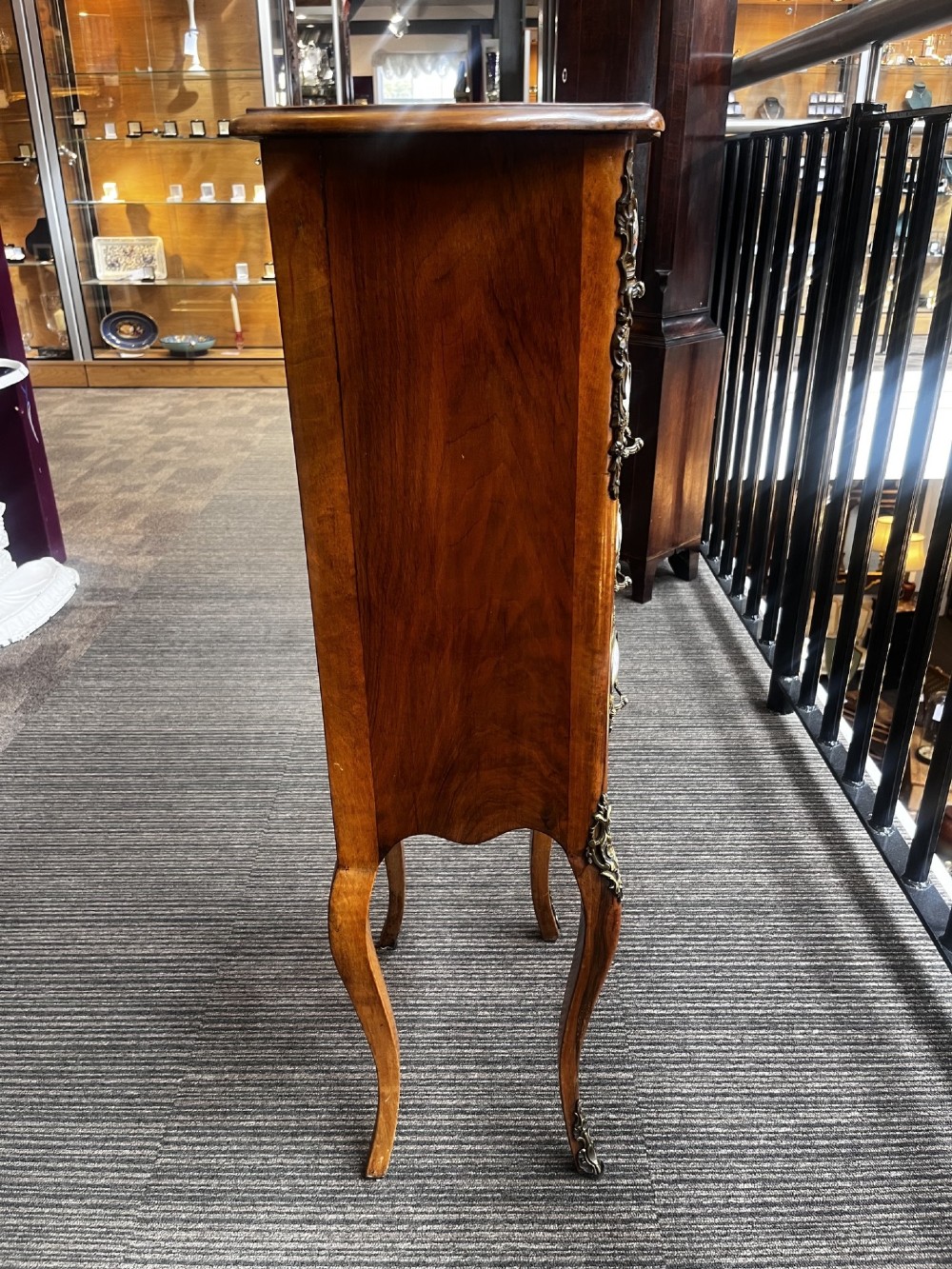 A late nineteenth-century walnut serpentine chest of four drawers featuring hand-painted oval porcelain plaques, ornate metal mounts, and slender cabriole legs. View VIII