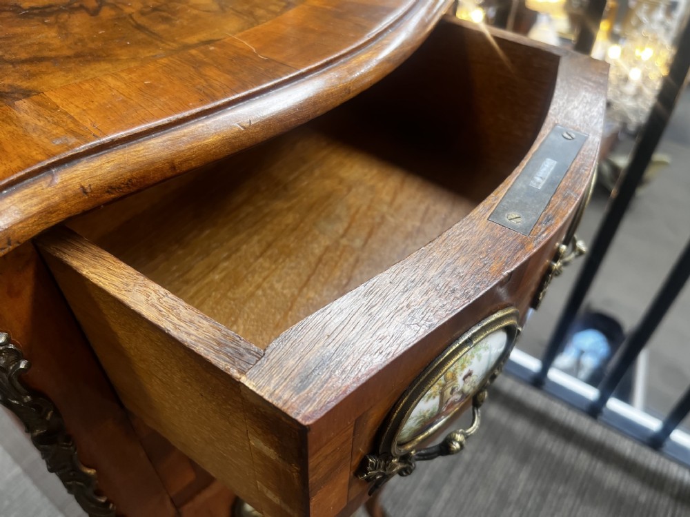 A late nineteenth-century walnut serpentine chest of four drawers featuring hand-painted oval porcelain plaques, ornate metal mounts, and slender cabriole legs. View IX