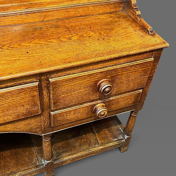 An early 19th-century dark oak Welsh dresser featuring a tall three-shelf open plate rack mounted on a base with five drawers, turned legs, and a lower pot board shelf. View II