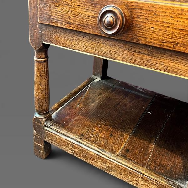 An early 19th-century dark oak Welsh dresser featuring a tall three-shelf open plate rack mounted on a base with five drawers, turned legs, and a lower pot board shelf. View VI