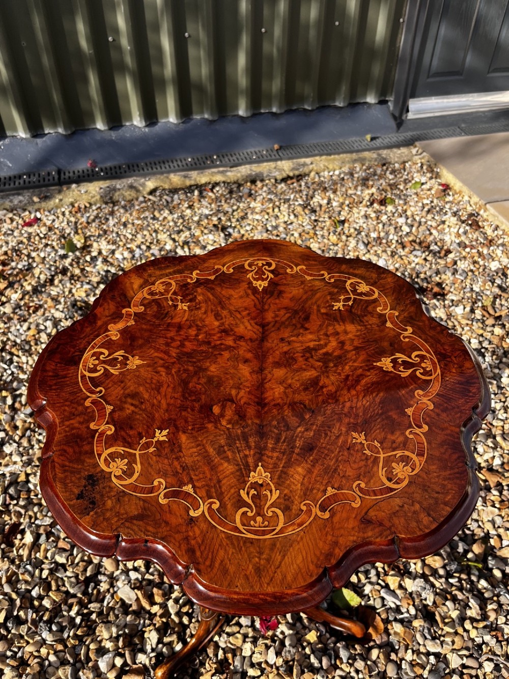 A Victorian burr walnut wine table featuring a scalloped top with floral marquetry inlay, a carved central pedestal, and tripod legs. View IX