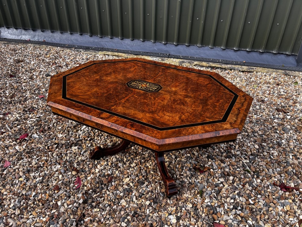 An octagonal Victorian burr walnut low coffee table with central floral marquetry inlay and splayed legs.