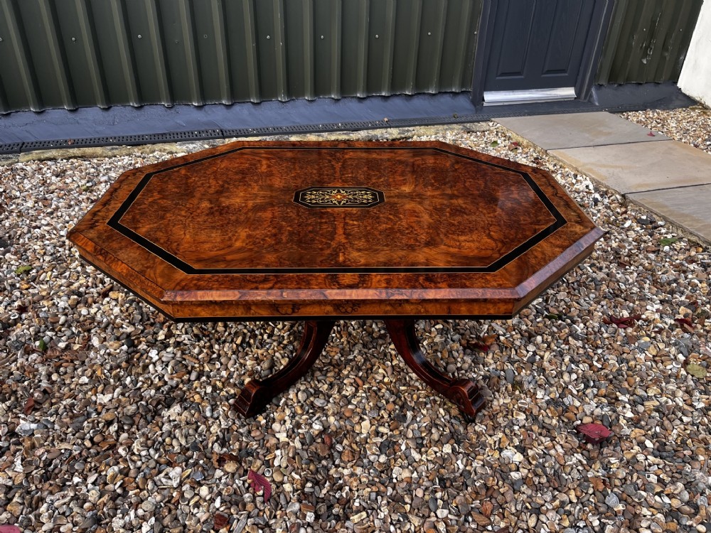 An octagonal Victorian burr walnut low coffee table with central floral marquetry inlay and splayed legs. View V