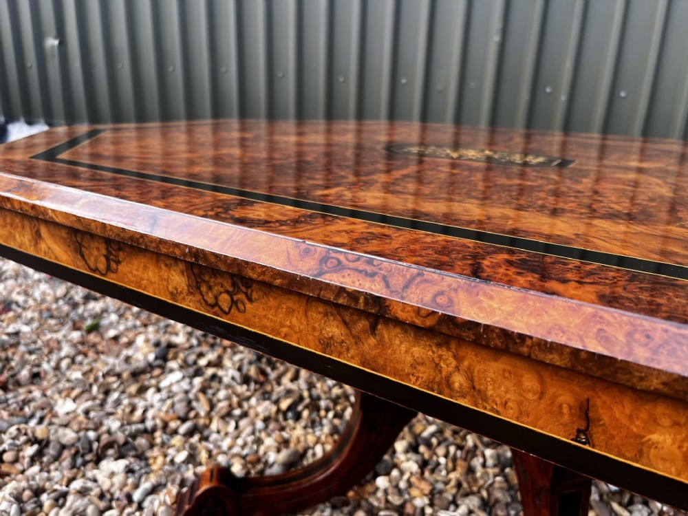 An octagonal Victorian burr walnut low coffee table with central floral marquetry inlay and splayed legs. View VI