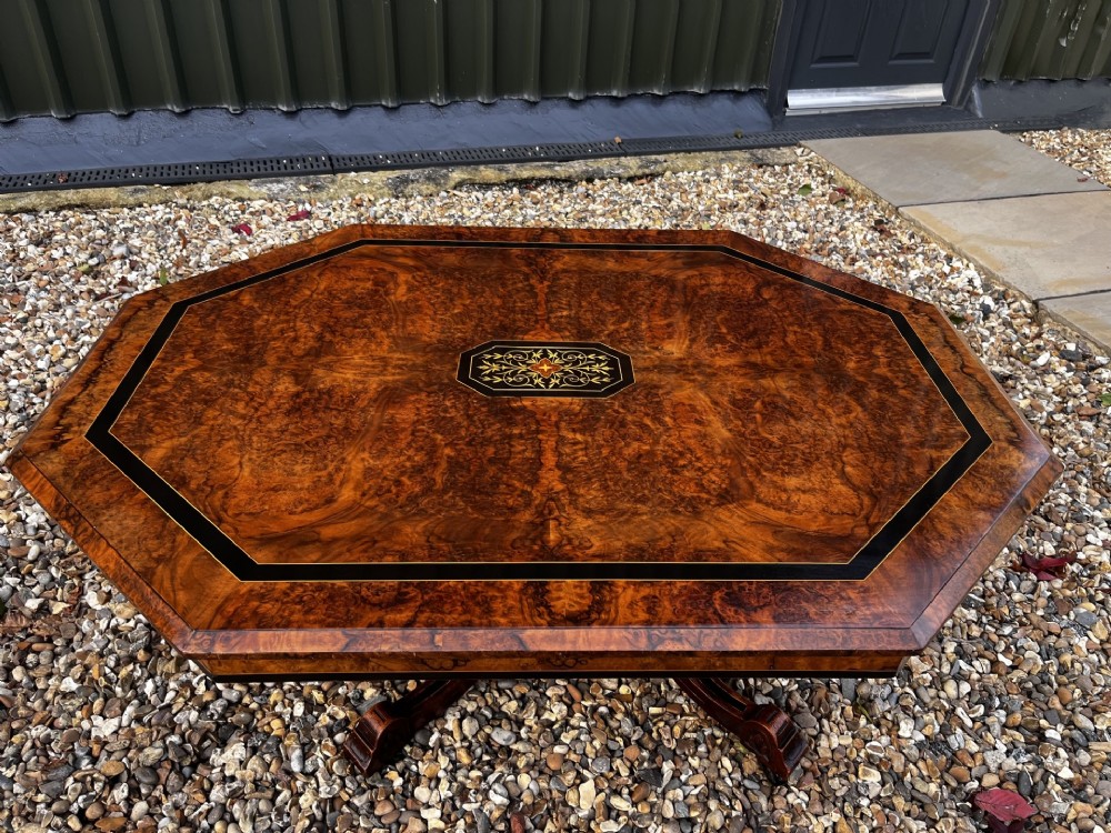 An octagonal Victorian burr walnut low coffee table with central floral marquetry inlay and splayed legs. View VII