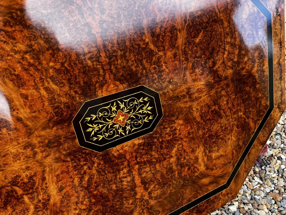 An octagonal Victorian burr walnut low coffee table with central floral marquetry inlay and splayed legs. View X